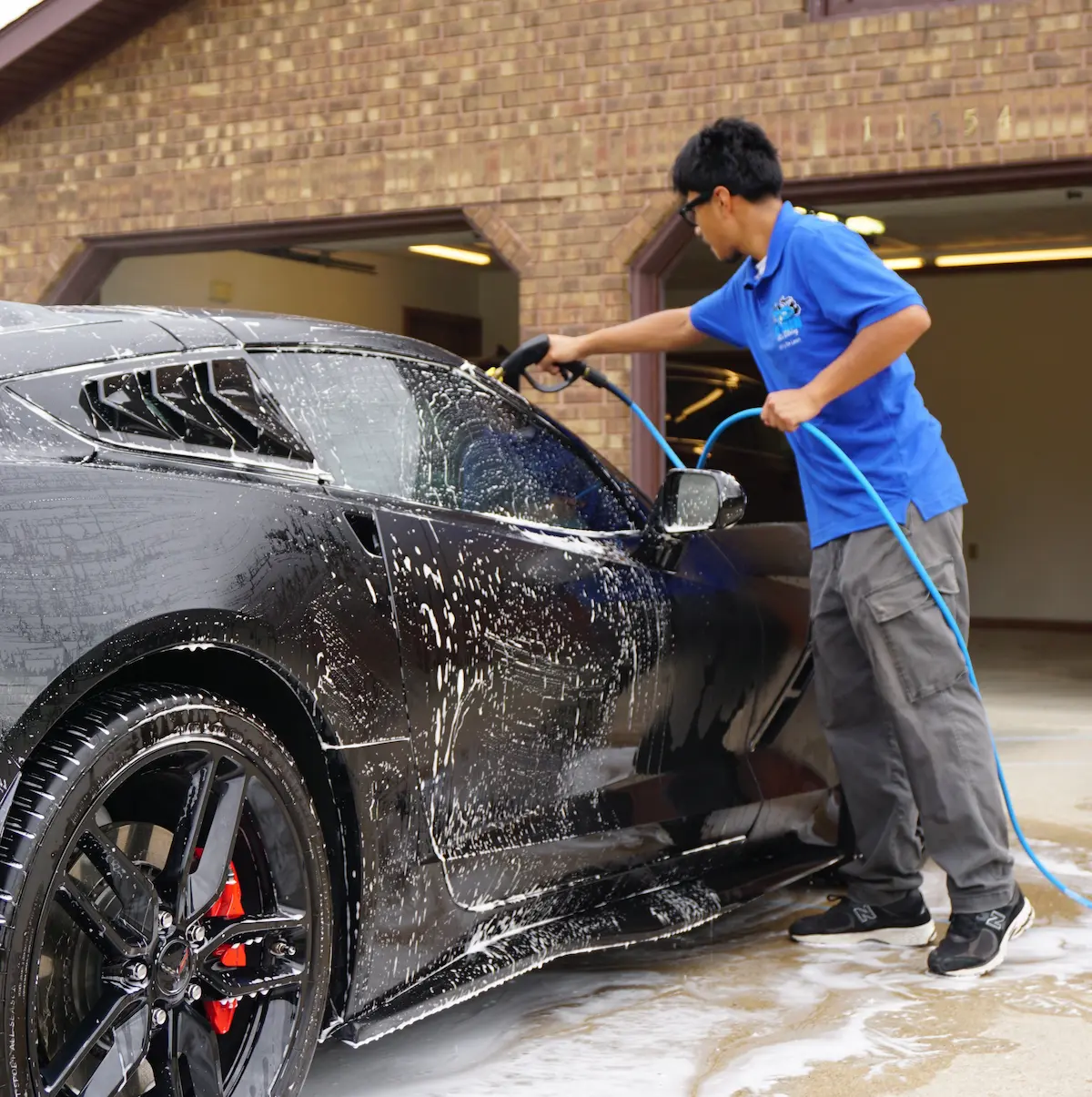 Professional mobile auto detailer hand-washing a luxury sports car in Grand Rapids, MI